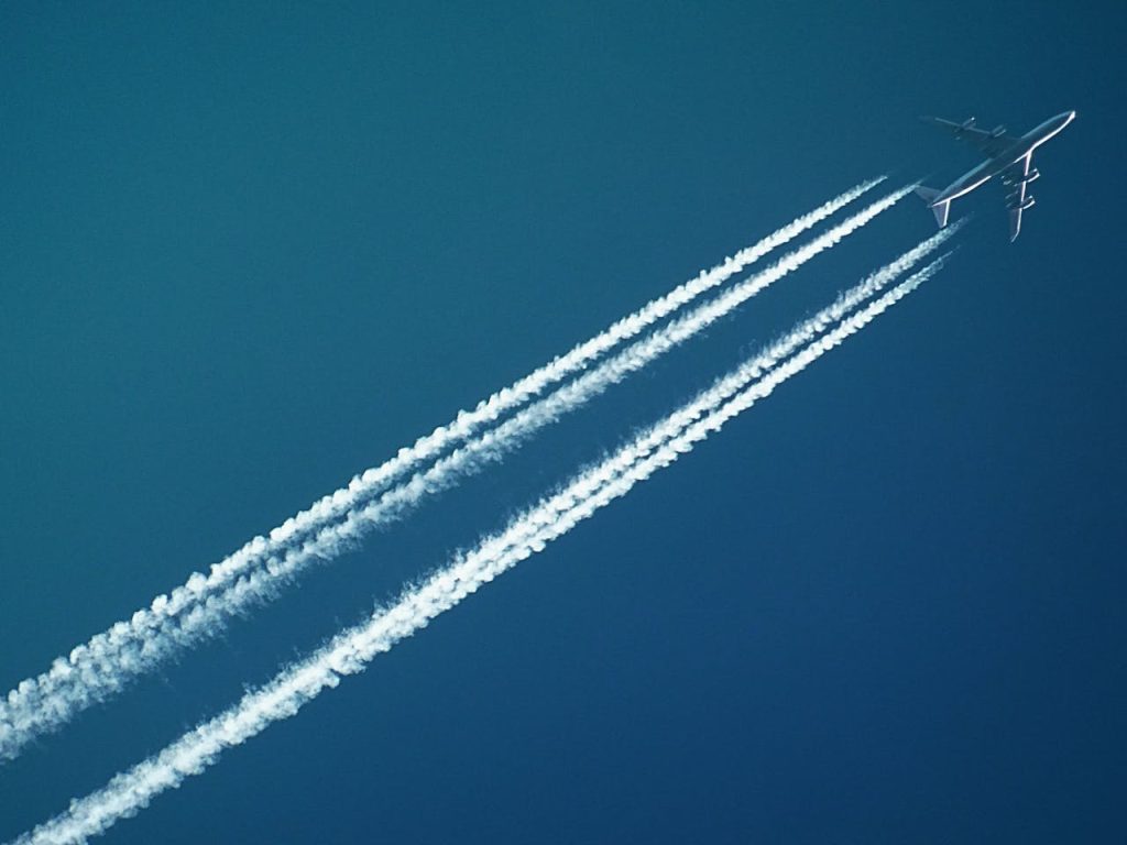 pexels-photo-728824 Aerial view of an airplane in flight, leaving vapor trails against a clear blue sky.